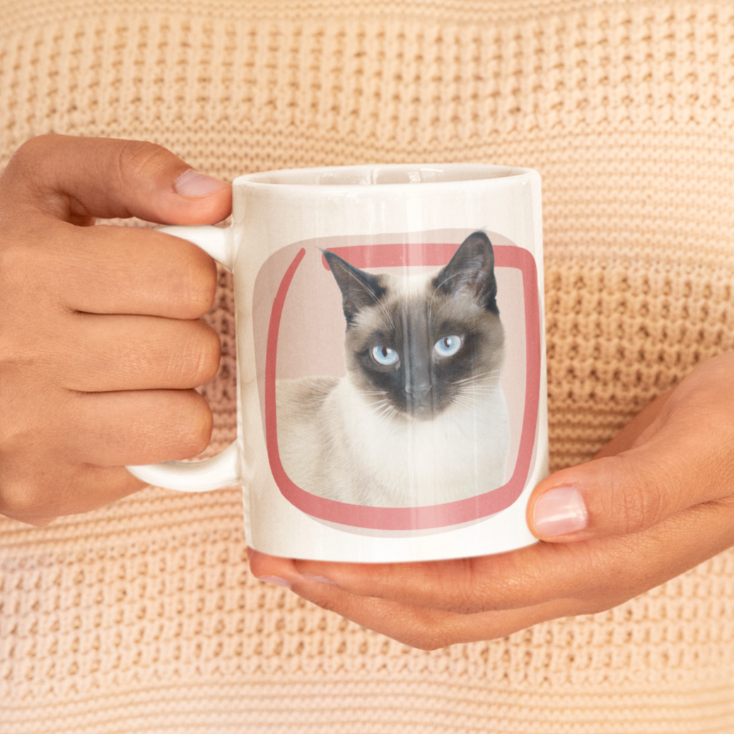 Woman holding a mug with a cat design in a kitchen setting
