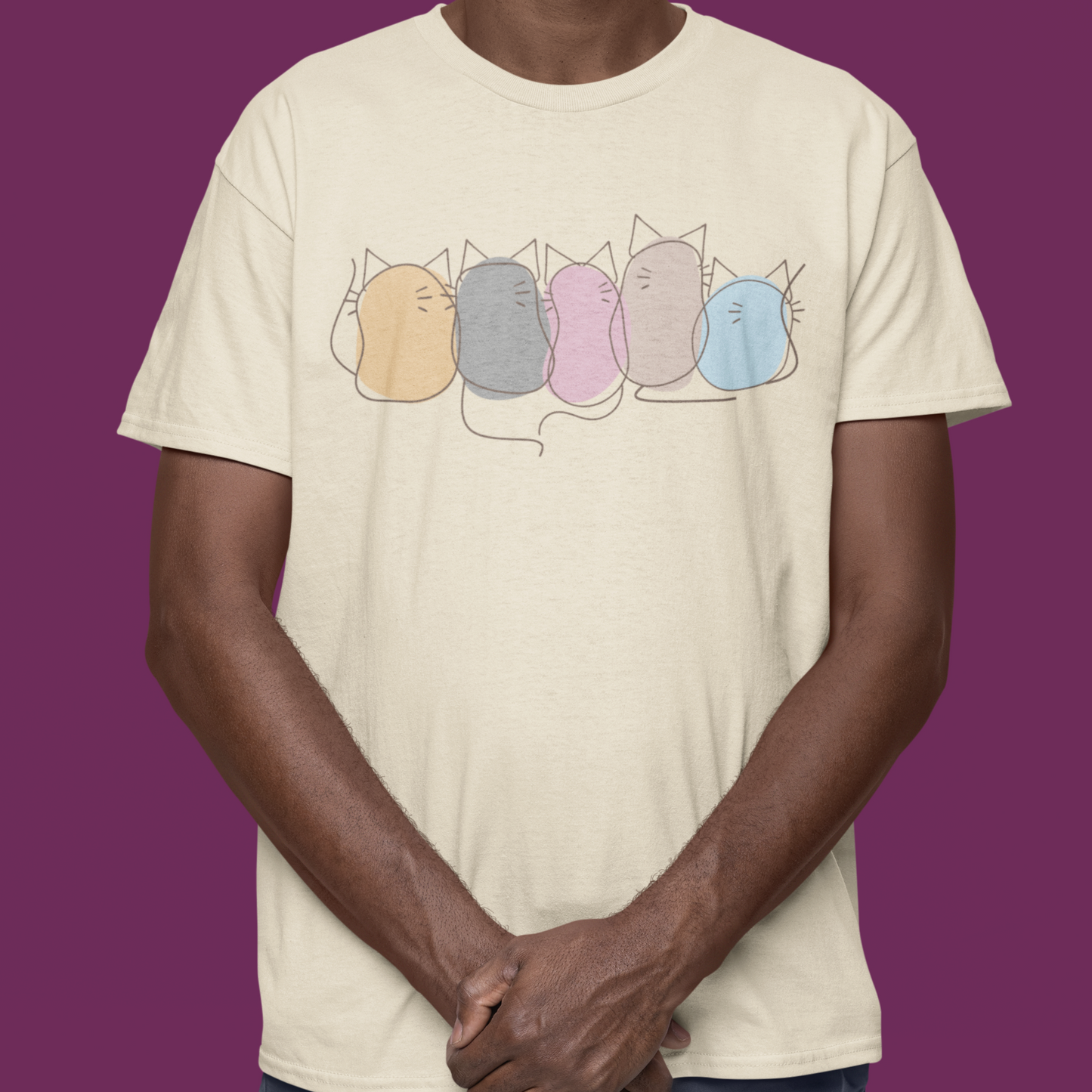 Man wearing a beige t-shirt with colorful cat illustrations on a purple background